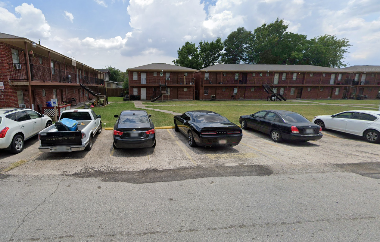 A parking lot with cars and apartment buildings in the background.