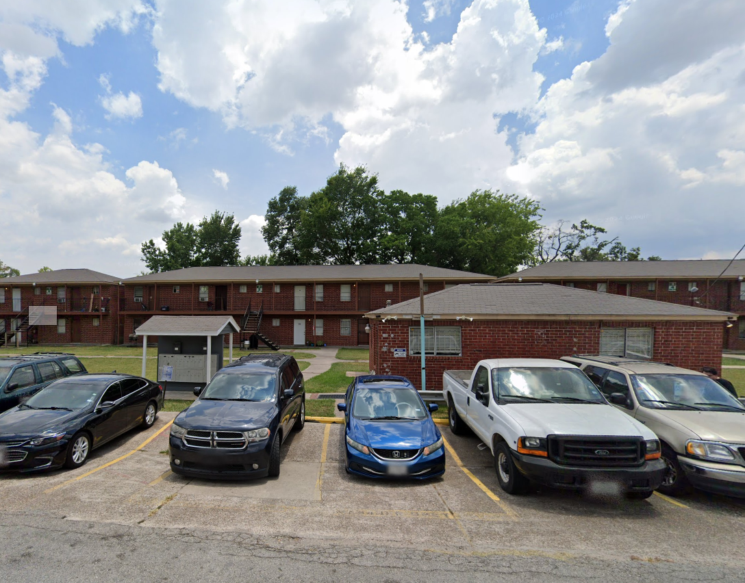 A parking lot with cars parked in front of a brick building.