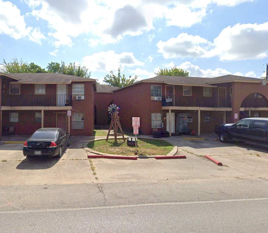A parking lot with a car and apartment buildings.