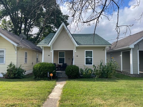 A house with a green roof and a white fence.