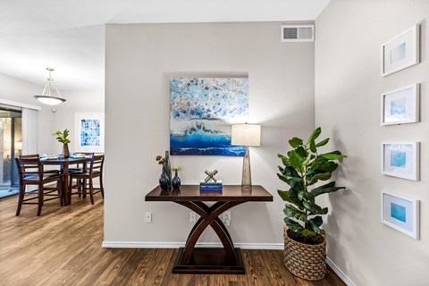 a living room with a dining room table and a painting on the wall