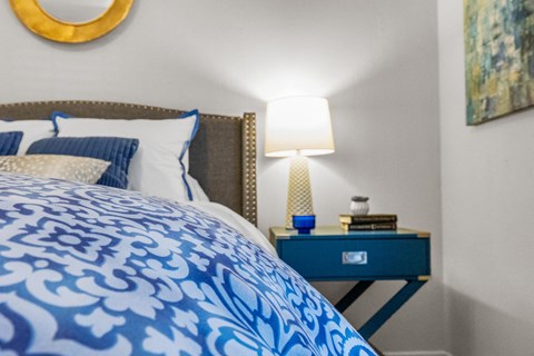 a bedroom with a blue and white bedspread and a nightstand with a lamp