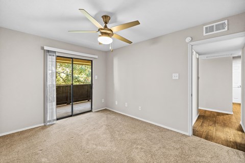 an empty living room with a ceiling fan and a door to a patio