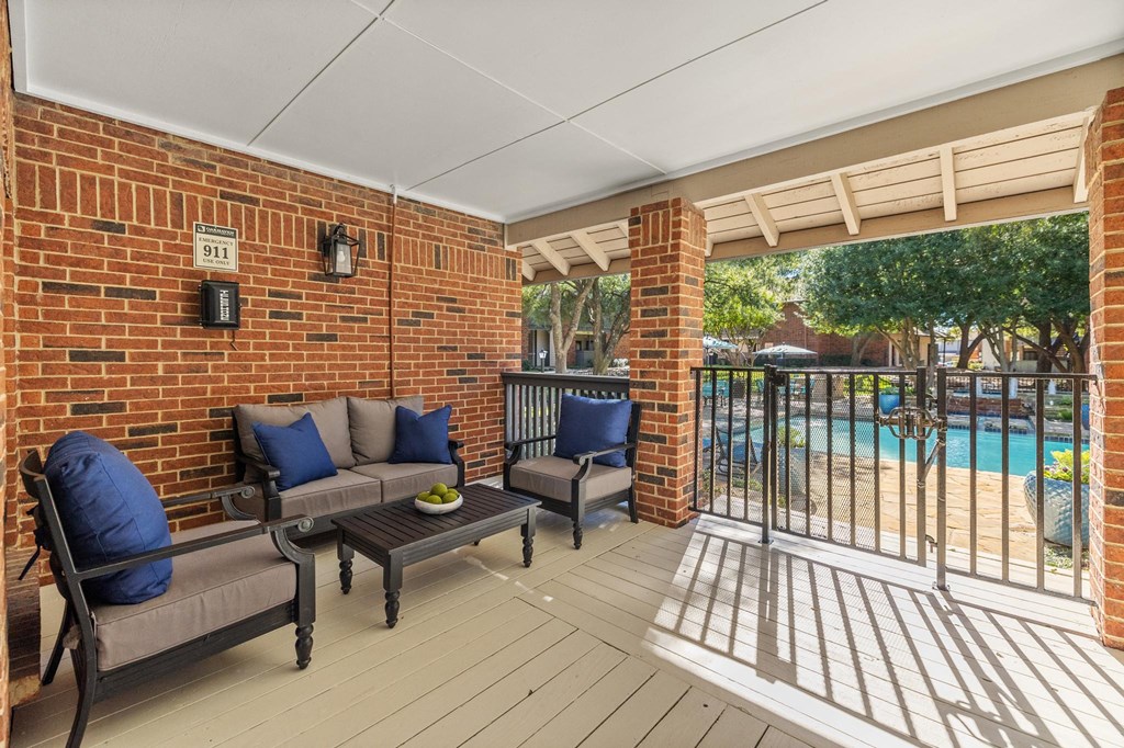 a covered patio with chairs and a pool in the background