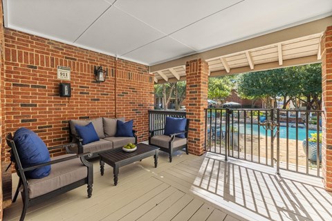 a covered patio with chairs and a pool in the background