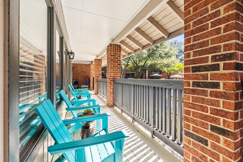 a porch with blue benches and a brick wall