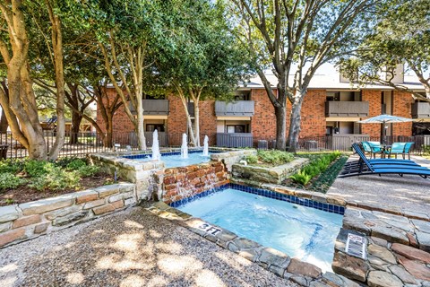 a resort style pool with a fountain and trees in a courtyard