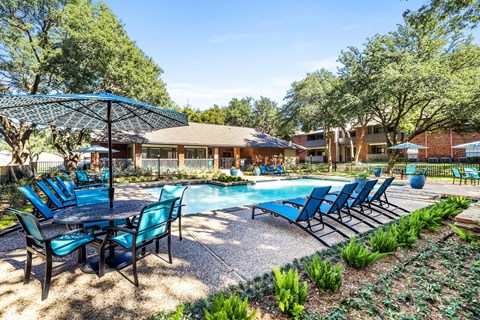 a swimming pool with blue chairs and umbrellas