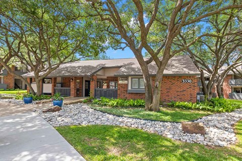 a house with trees and a sidewalk in front of it
