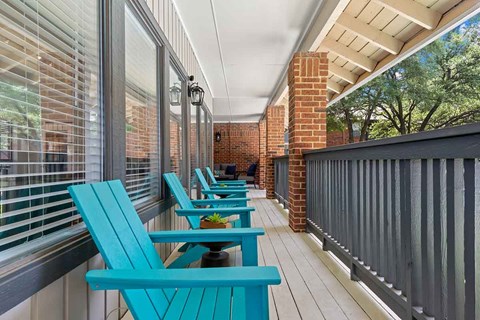 a porch with blue chairs and a balcony with a brick wall