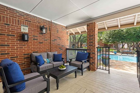 a covered patio with a pool and a brick wall