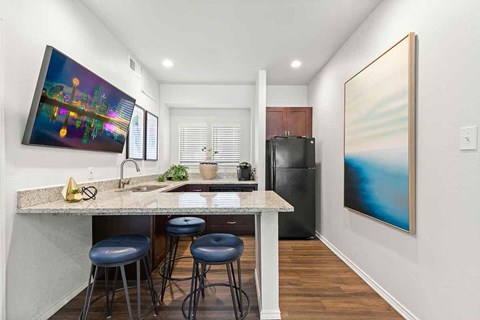 a kitchen with a counter and stools and a refrigerator