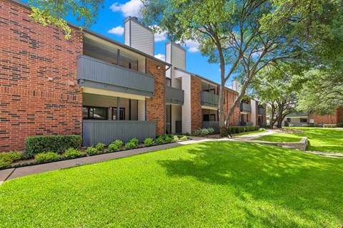 an apartment building with green grass and trees