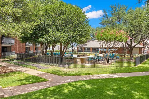 a yard with a fenced in area with picnic tables   and a house