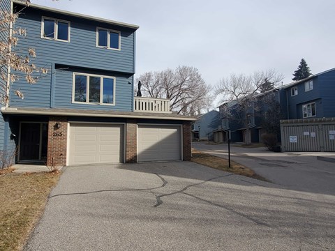 A blue house with a white garage door is numbered 265.