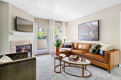 A living room with a brown couch, a fireplace, and a painting on the wall.