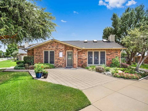 the front of a brick house with a driveway and grass