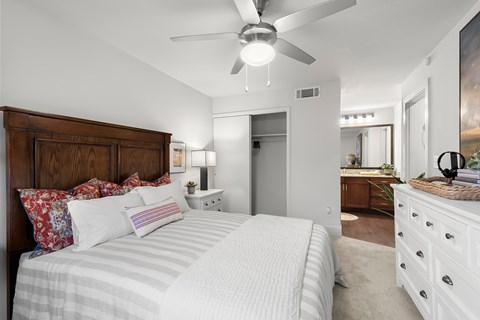 A bedroom with a large bed and a ceiling fan.
