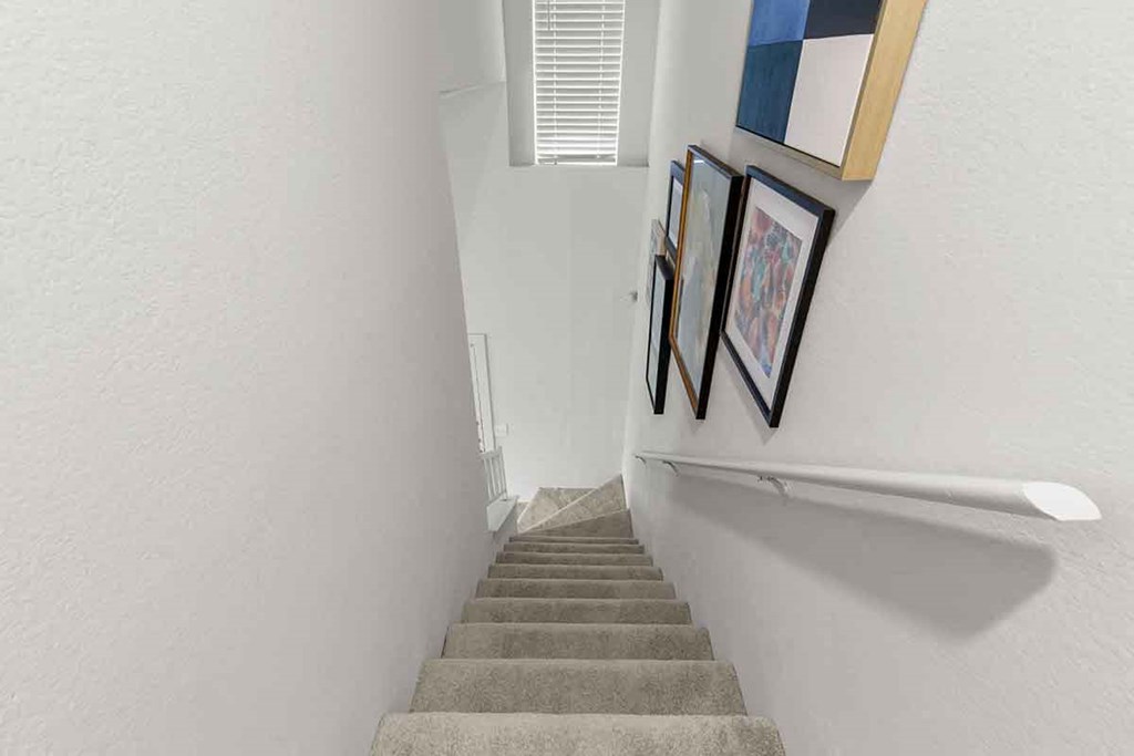 stairs leading up to a hallway with pictures on the wall