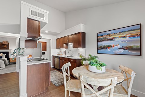 A kitchen with a table and chairs and a painting on the wall.