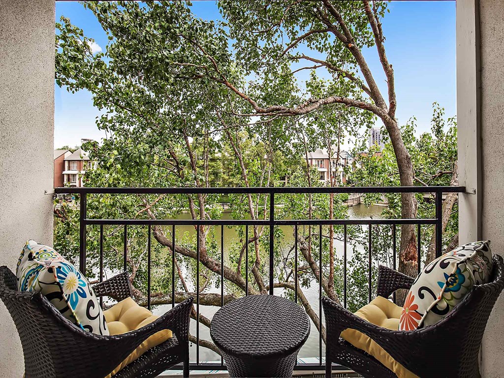 a balcony with chairs and a view of a river and trees