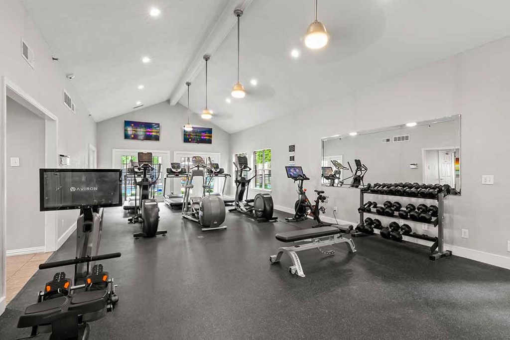 a gym with cardio equipment and weights on the floor