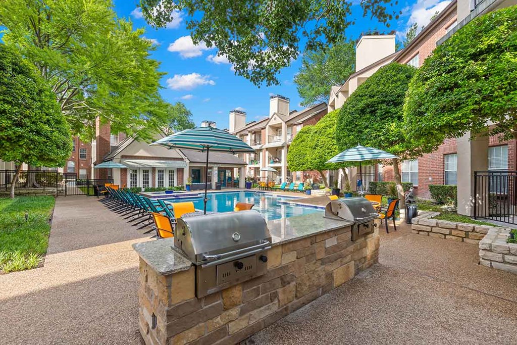a resort style swimming pool with a grill and lounge chairs