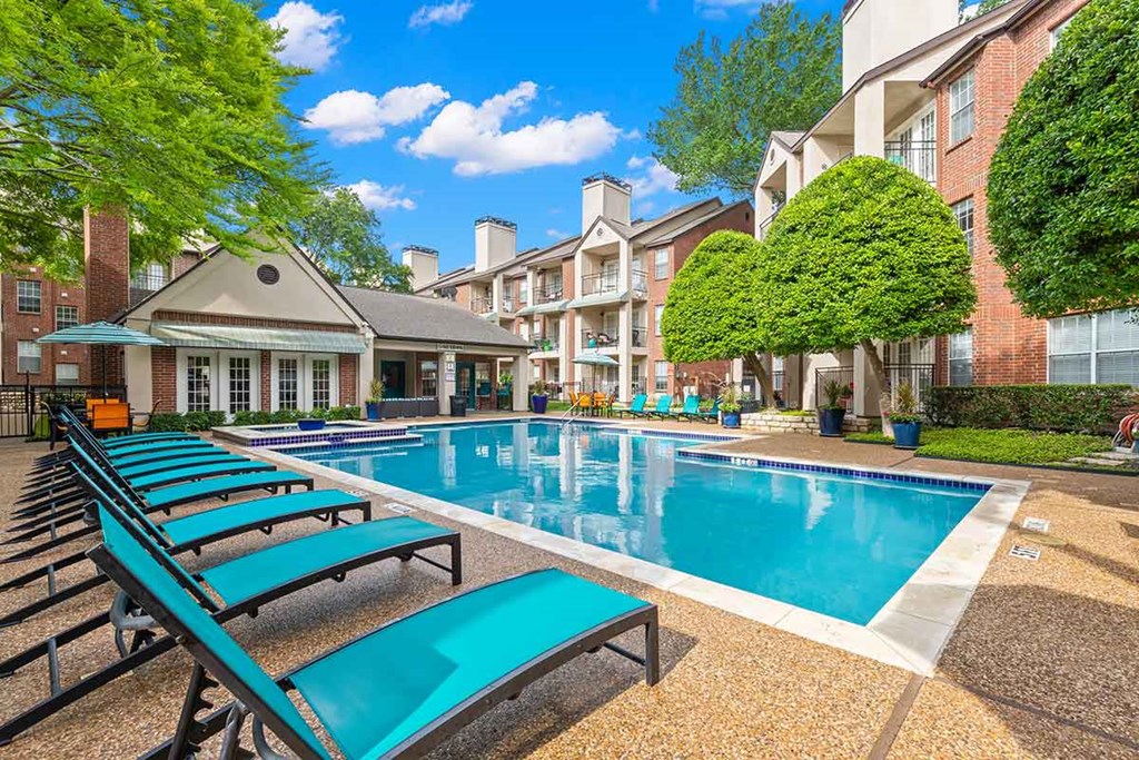 an outdoor swimming pool with blue chairs and a building in the background