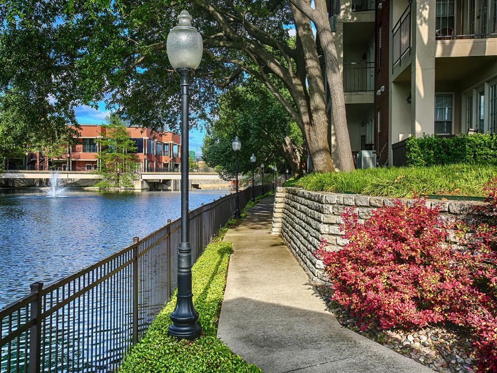 a walkway next to a river next to an apartment building