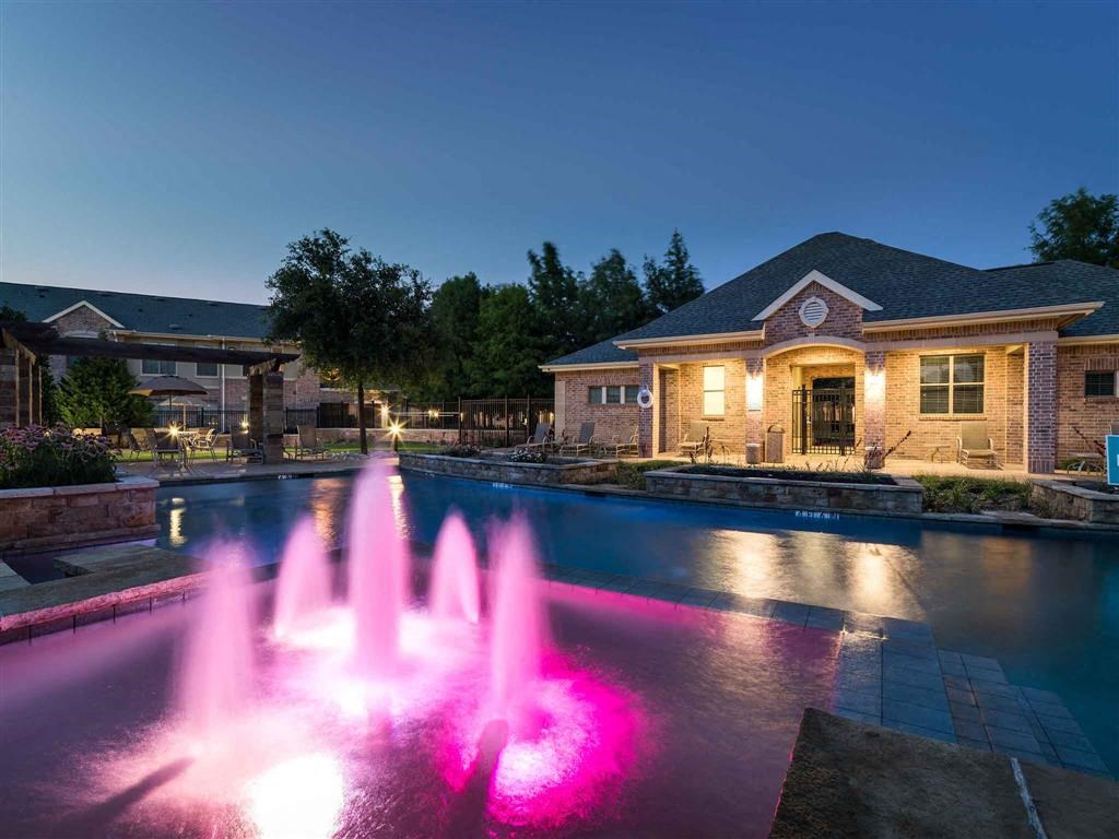 a pool with a fountain in front of a house