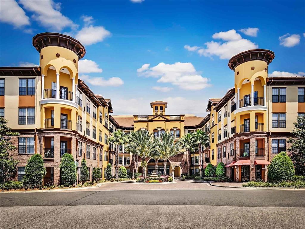 a view of the exterior of an apartment building with palm trees