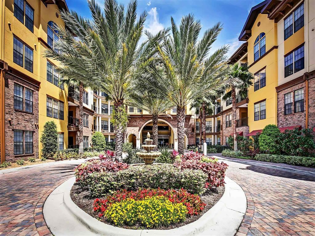 a courtyard with palm trees and flowers in front of a building