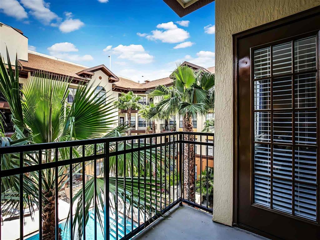 a balcony with a view of a pool and palm trees