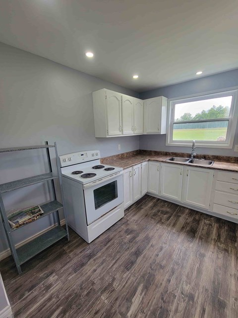A kitchen with a white stove and wooden flooring.