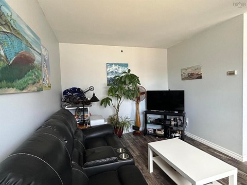 A living room with a black leather couch and a white coffee table.