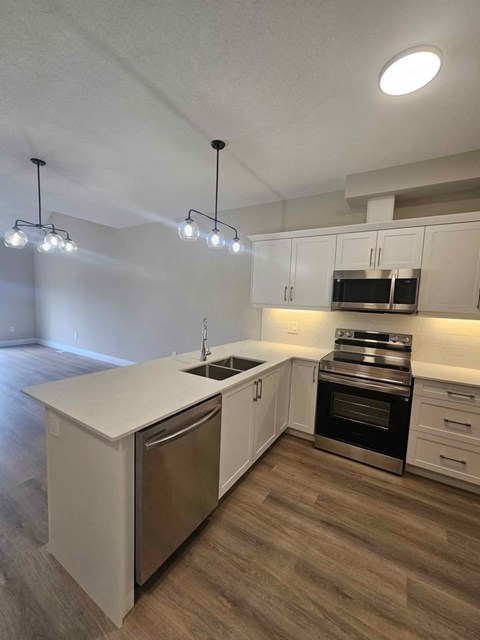 A modern kitchen with white cabinets and stainless steel appliances.