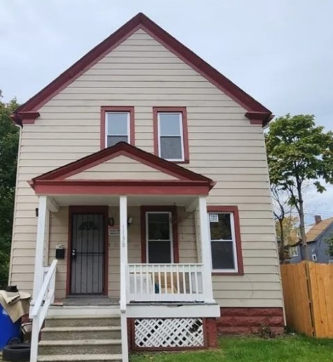 A small house with a red roof and a porch.