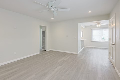 A spacious room with a ceiling fan and lighting fixture.