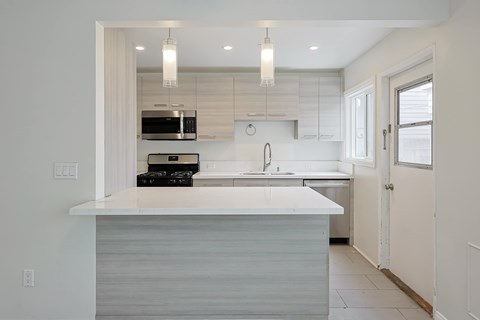 A modern kitchen with a white countertop and a sink.