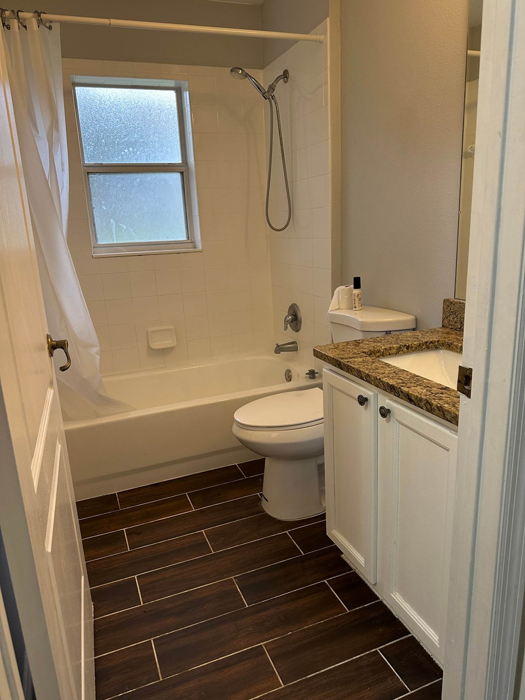 A white toilet sits in a bathroom with a brown tile floor.
