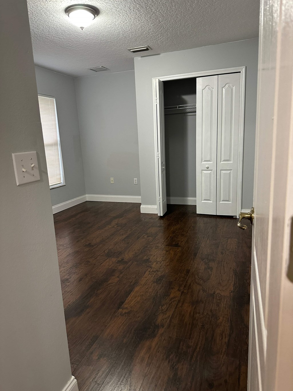 A room with a white door and wooden flooring.