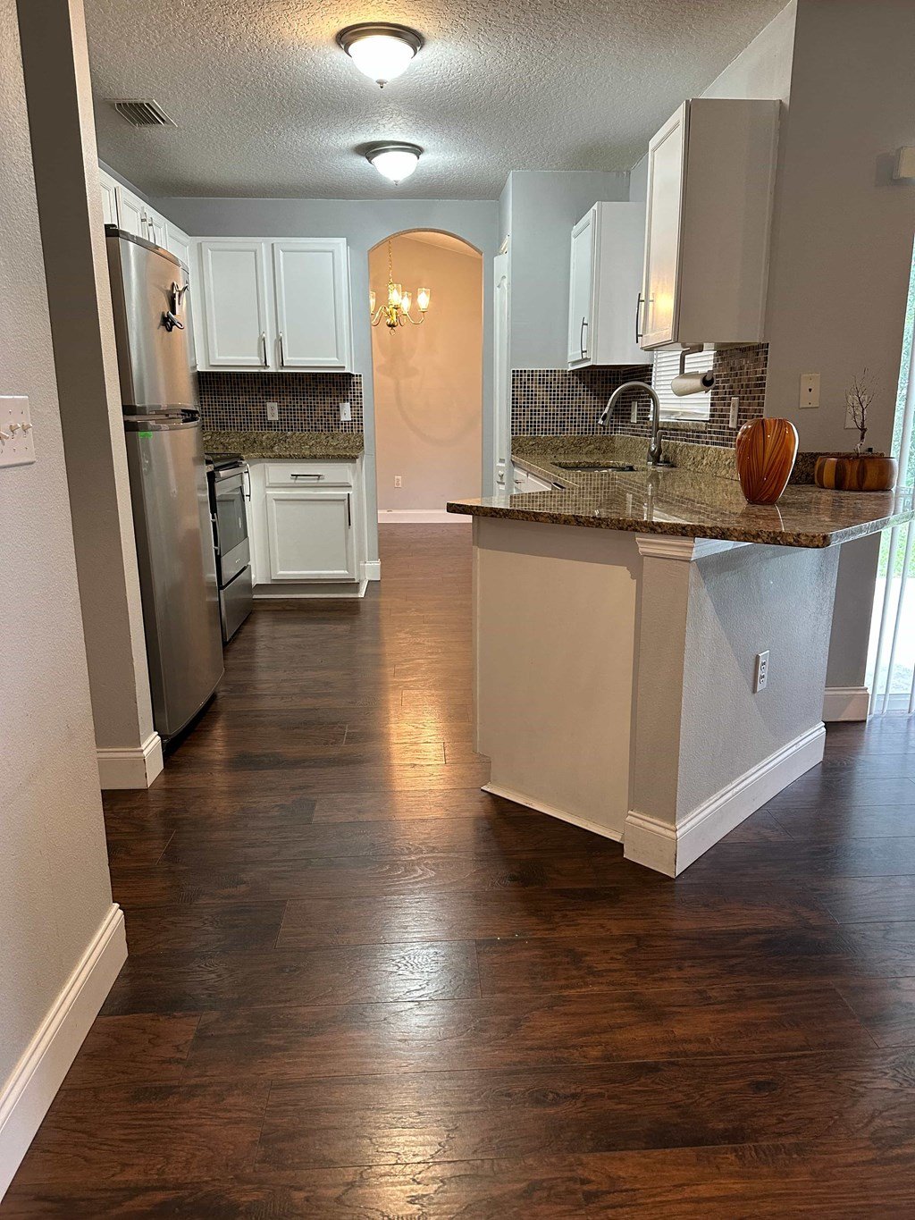 A kitchen with a white counter and wooden floors.