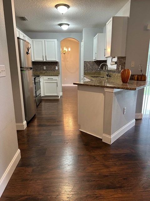 A kitchen with a white counter and wooden floors.