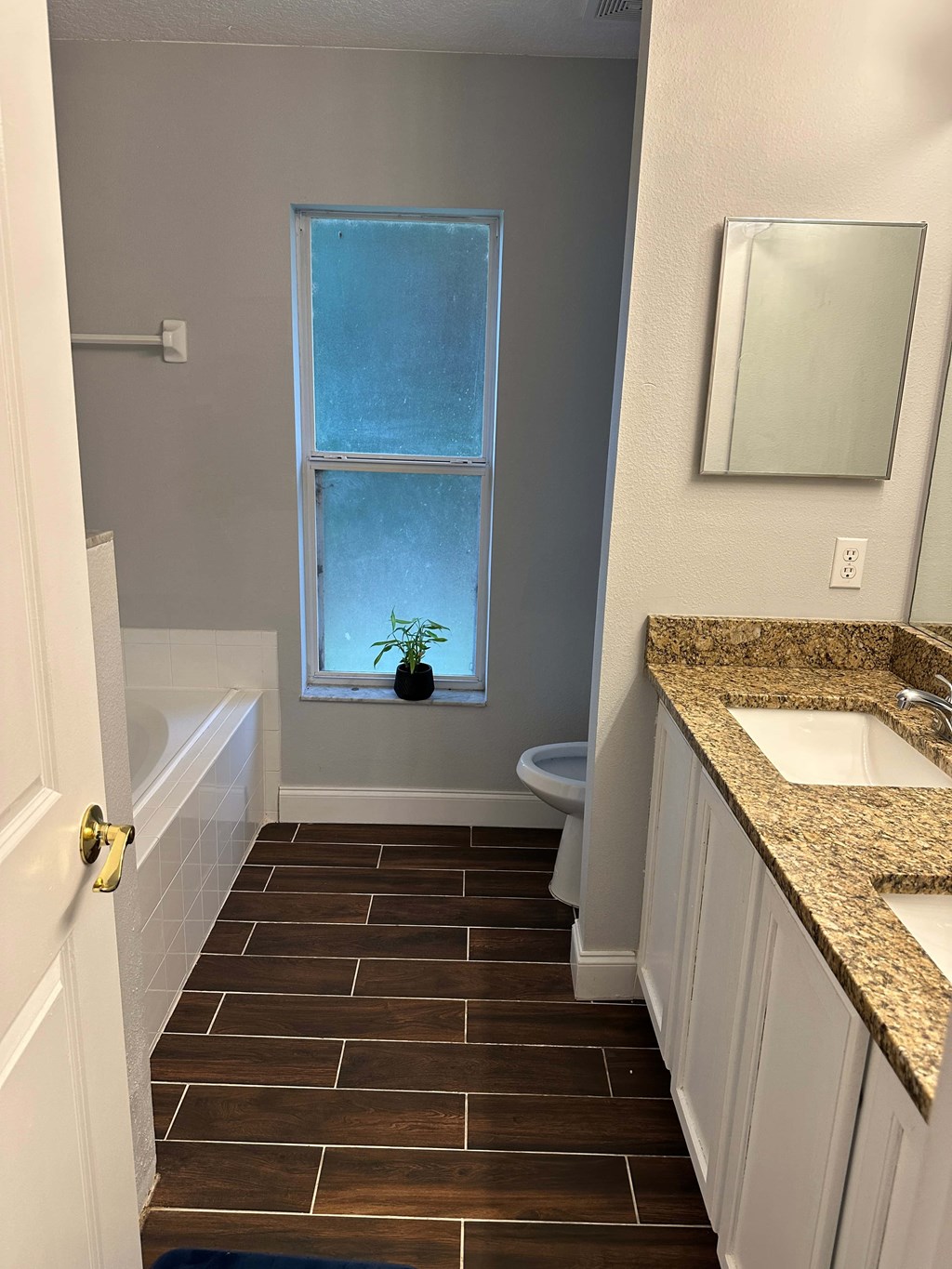 A bathroom with a toilet, sink, and a window.