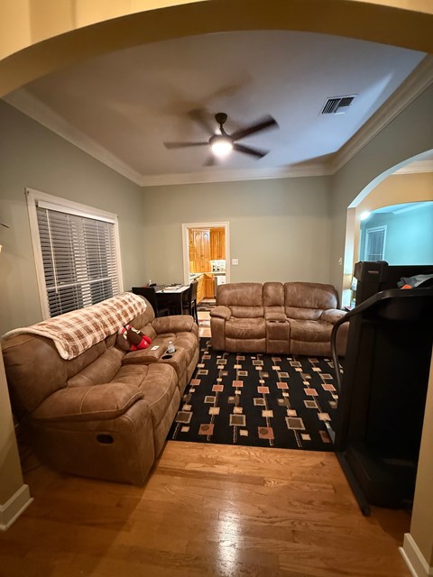 A living room with a brown couch and a black television.