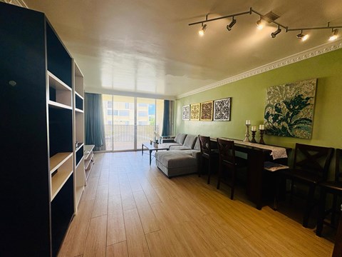 A living room with a grey couch, wooden floors, and a large window.