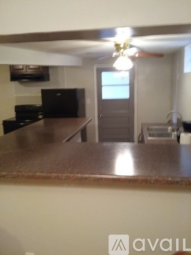 A kitchen with a brown counter top and a black fridge.