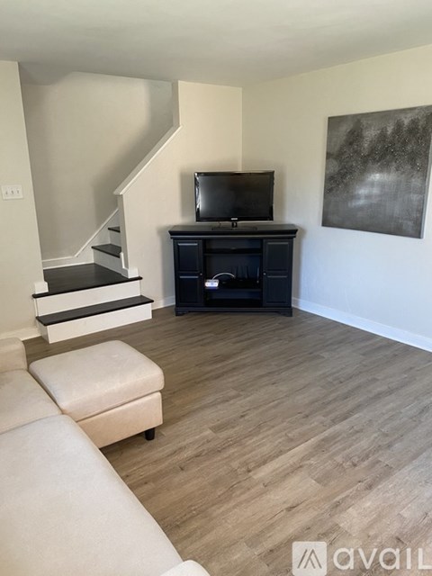 A living room with a white sofa and a black entertainment center.