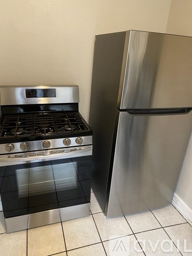 A stainless steel refrigerator stands next to a stove in a kitchen.