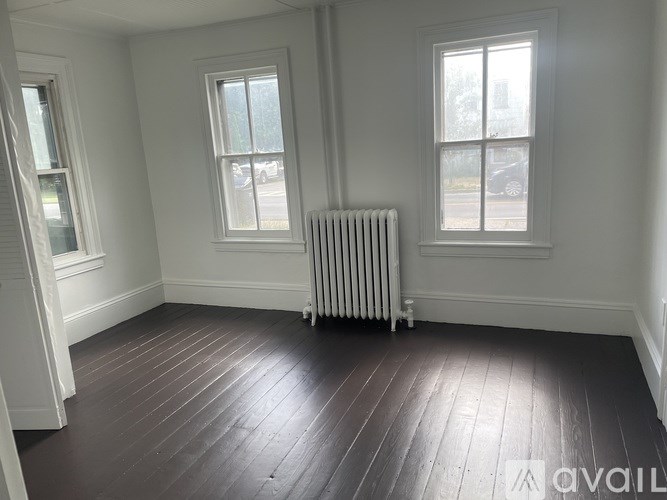 A room with a wooden floor and two windows.